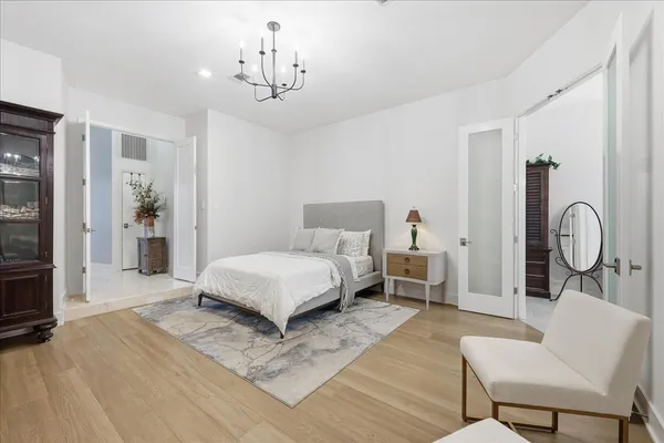 a bedroom with a bed mirror and a chandelier
