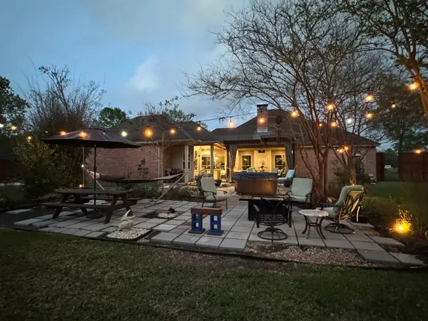 a view of a patio with table and chairs potted plants and large tree