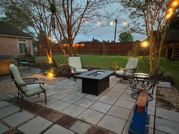 a view of a patio with table and chairs and a barbeque with potted plants and large trees