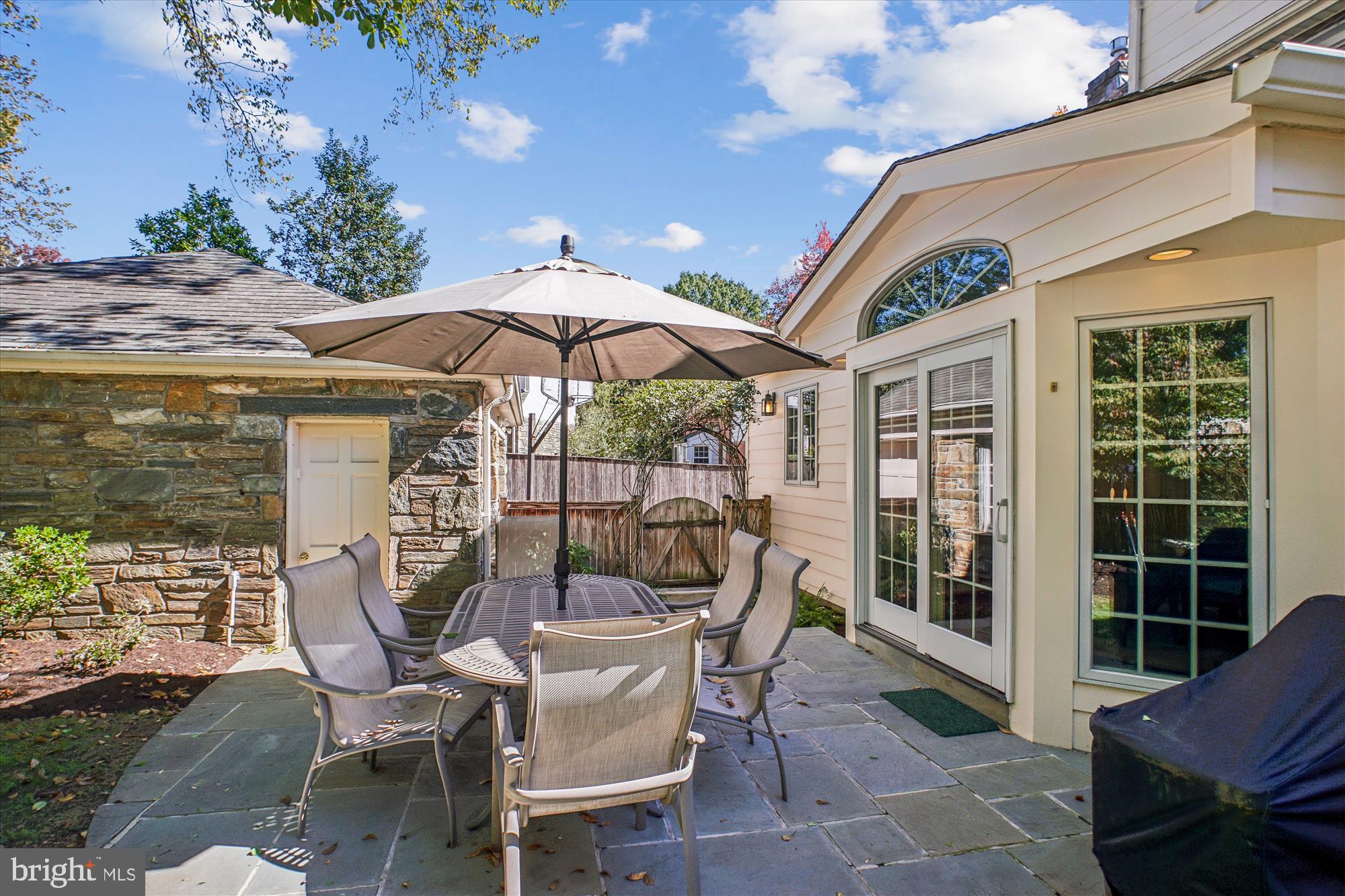 5103 Fairglen Lane Chevy Chase, MD 20815 - Photo 12 of 41 a view of a patio with a dining table and chairs under an umbrella with a fire pit