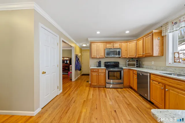 a kitchen with stainless steel appliances granite countertop a stove top oven a sink dishwasher and a refrigerator with wooden floor