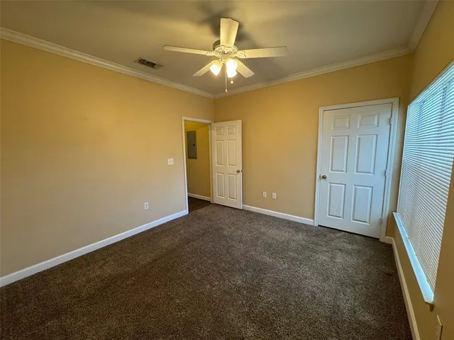 an empty room with a chandelier fan and windows