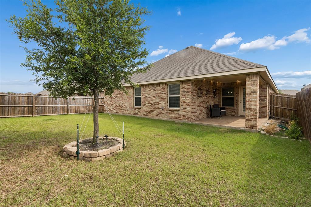 2850 Dusty Road Forney, TX 75126 - Photo 11 of 11 Expansive backyard featuring a covered patio, full brick exterior, privacy fencing, and a mature tree with a stone-edged planting bed