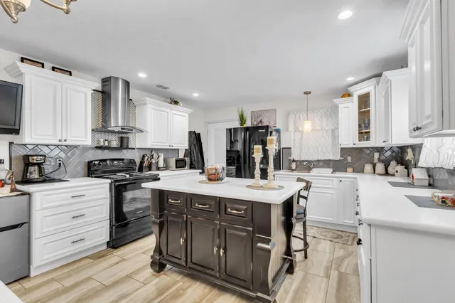 a kitchen with stainless steel appliances kitchen island granite countertop a sink stove and refrigerator