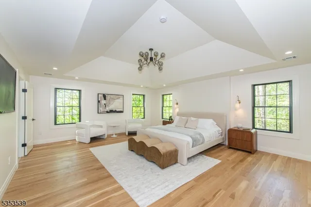 a spacious bedroom with a large bed a flat tv screen and dresser