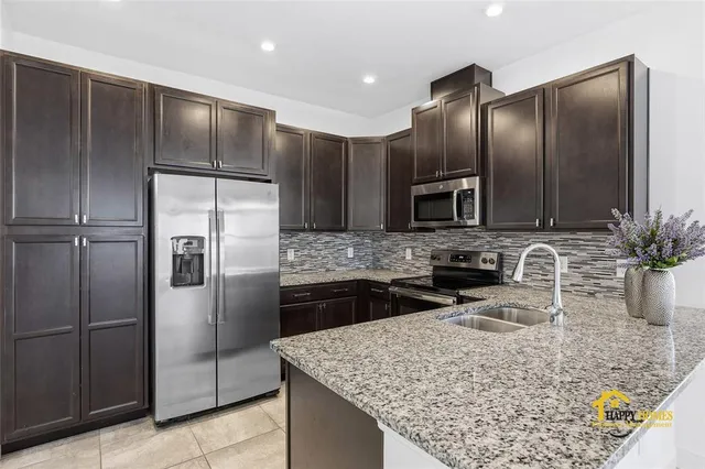 a kitchen with stainless steel appliances granite countertop a sink refrigerator and microwave