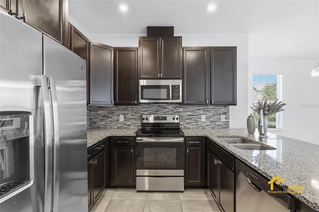 a kitchen with stainless steel appliances granite countertop a refrigerator and a sink