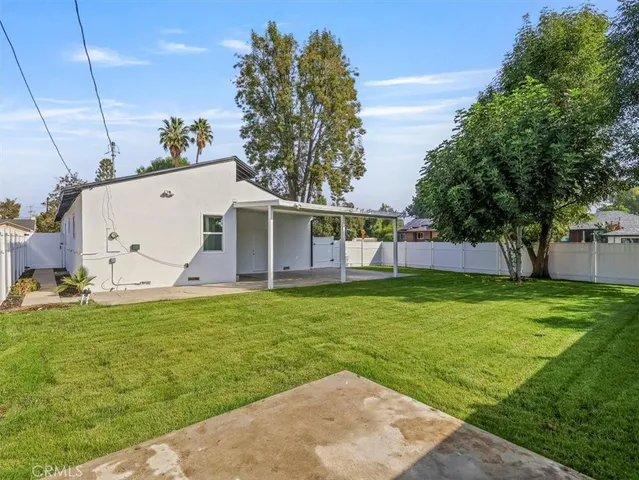 a view of a white house with a big yard potted plants and large tree