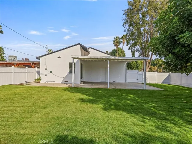 a backyard of a house with plants and large tree
