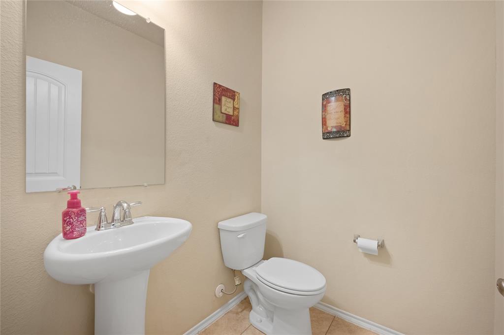 520 Rustic Oak Lane McKinney, TX 75072 - Photo 6 of 30 Pedestal sink with chrome faucet, a rectangular wall-mounted mirror, and tile flooring