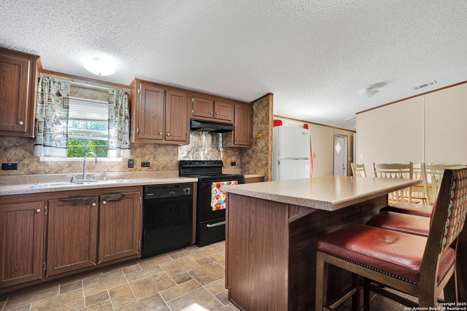 7176 Burshard Road San Antonio, TX 78263 - Photo 9 of 20 a kitchen with stainless steel appliances a table chairs sink refrigerator and cabinets