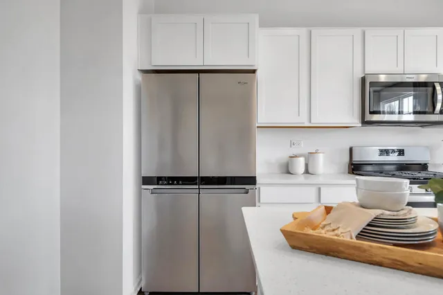 a kitchen with a refrigerator and white cabinets