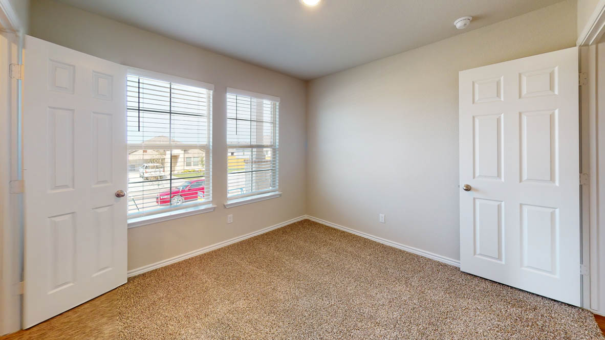 429 Creekfall Road Burnet, TX 78611 - Photo 24 of 28 A well-lit bedroom features plush carpeting and multiple windows.