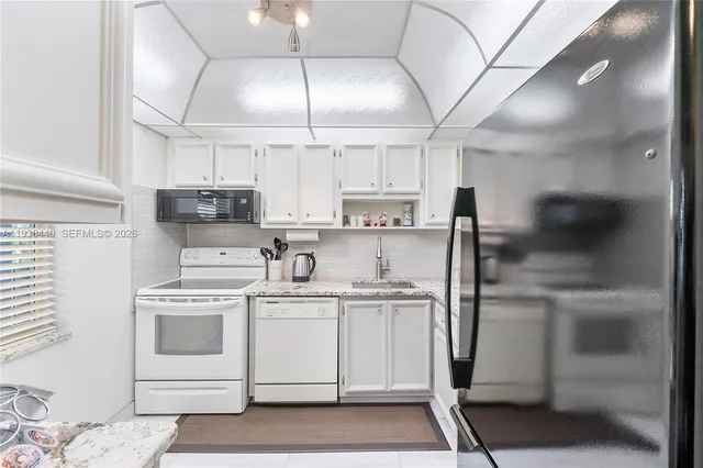 a kitchen with a sink a refrigerator and cabinets