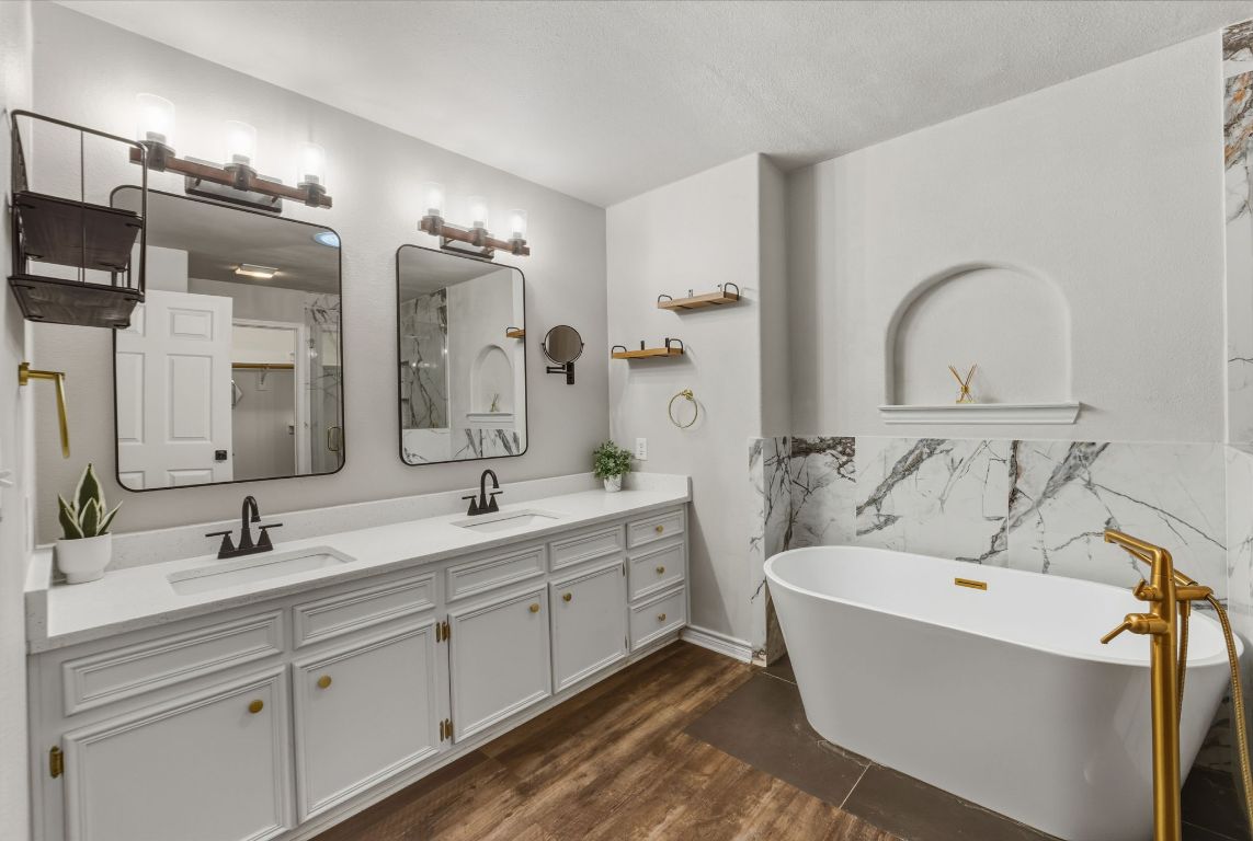 20808 Sandy Brown Lane Webberville, TX 78621 - Photo 13 of 40 a bathroom with a double vanity sink a mirror and a bathtub