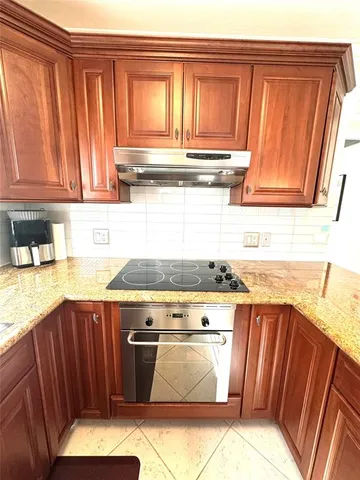 a kitchen with granite countertop wooden cabinets and a stove top oven