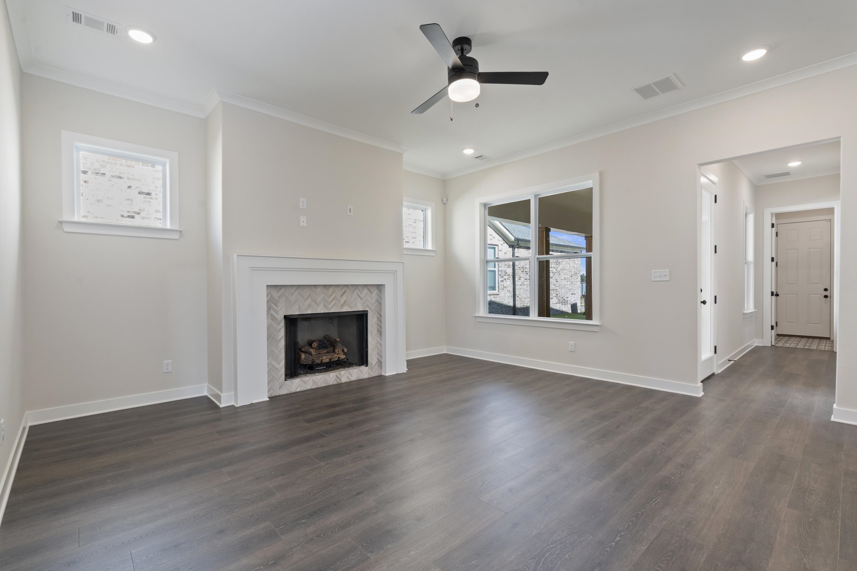 4844 Lyla Lane Collierville, TN 38017 - Photo 12 of 31 Unfurnished living room featuring dark wood-type flooring, recessed lighting, crown molding, ceiling fan, and a fireplace