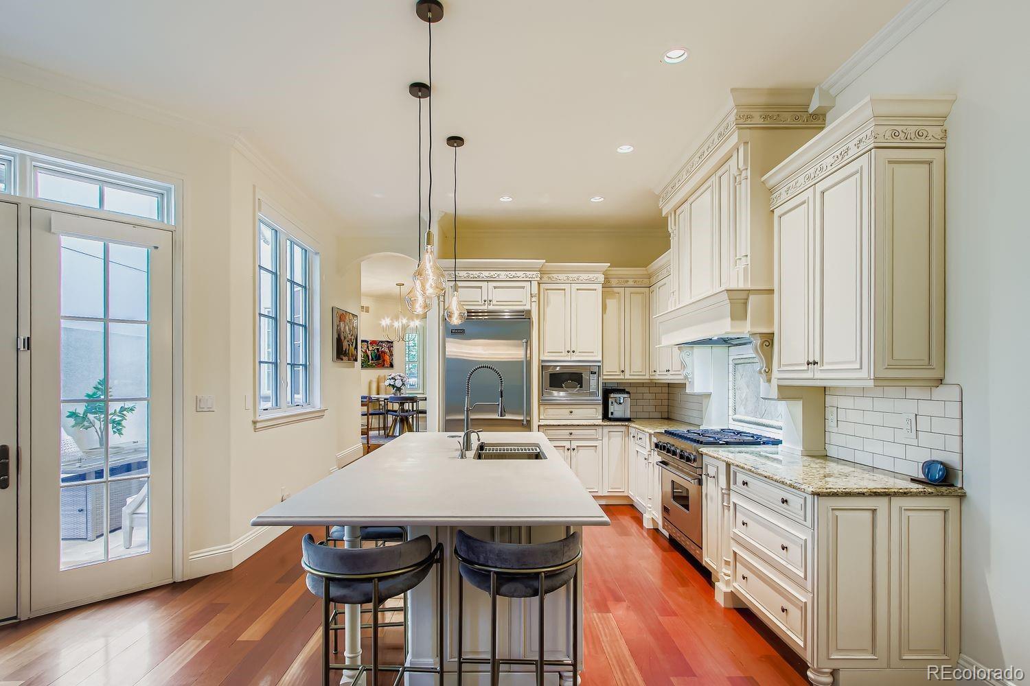 450 Detroit Street Denver, CO 80206 - Photo 5 of 28 a kitchen with stainless steel appliances a table chairs refrigerator and cabinets