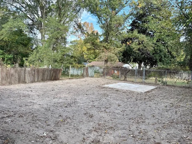 a view of a yard with large tree and wooden fence