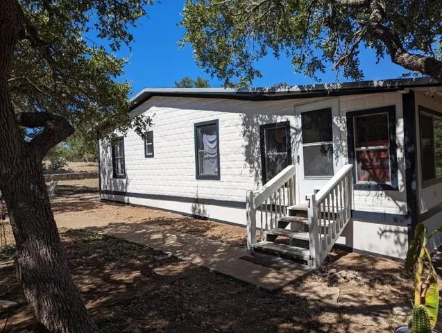 a front view of a house with a tree