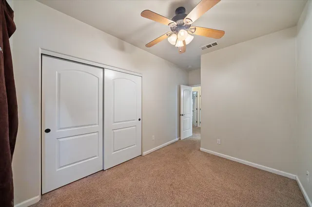 an empty room with a fan & a ceiling fan