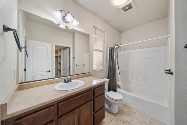 a bathroom with a granite countertop sink a toilet a mirror and shower