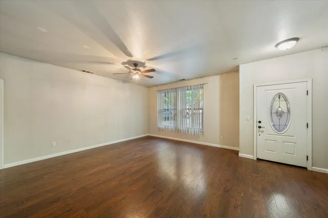 a view of an empty room with a window and wooden floor