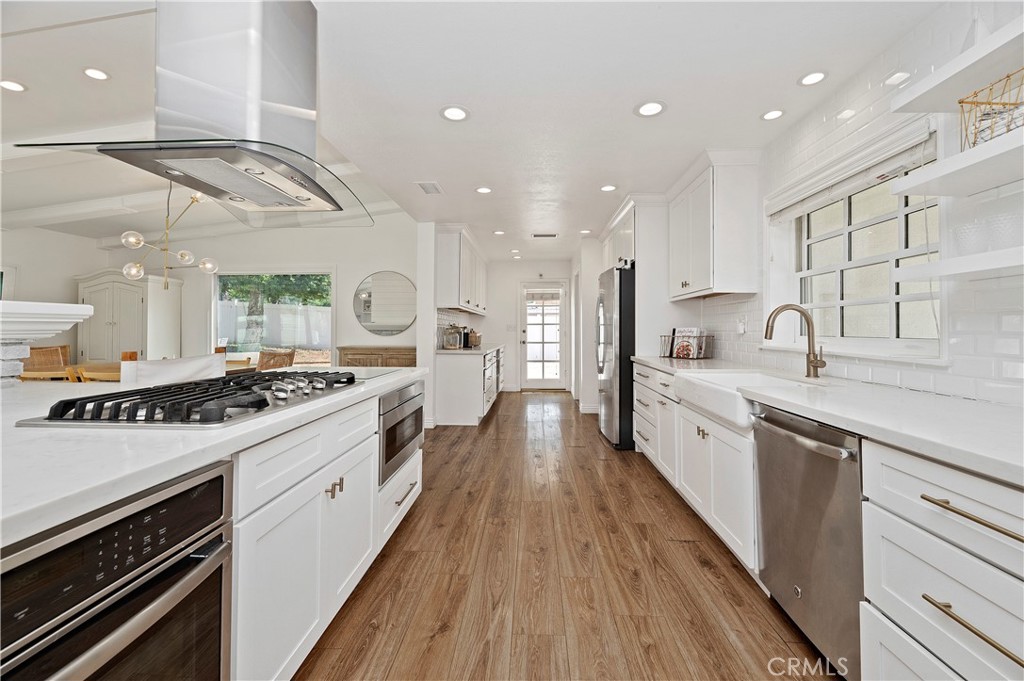 7398 Whitegate Avenue Riverside, CA 92506 - Photo 13 of 51 a large kitchen with stainless steel appliances granite countertop a lot of counter space and wooden floors