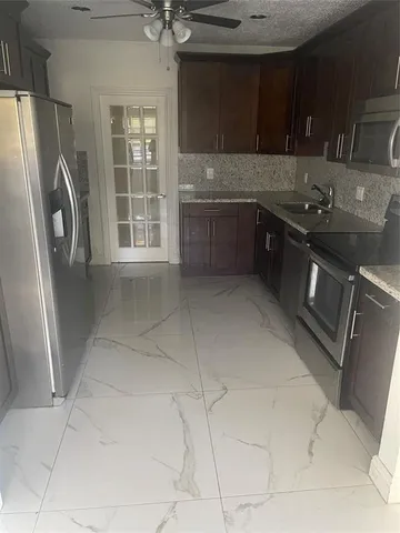 a kitchen with stainless steel appliances granite countertop a refrigerator and a sink