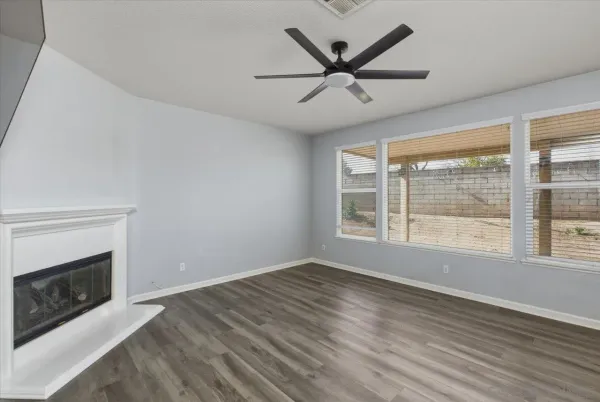 a view of a big room with wooden floor a ceiling fan and windows