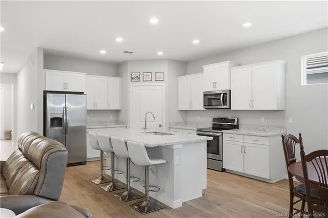 a kitchen with stainless steel appliances granite countertop a sink a stove a refrigerator cabinets and chairs