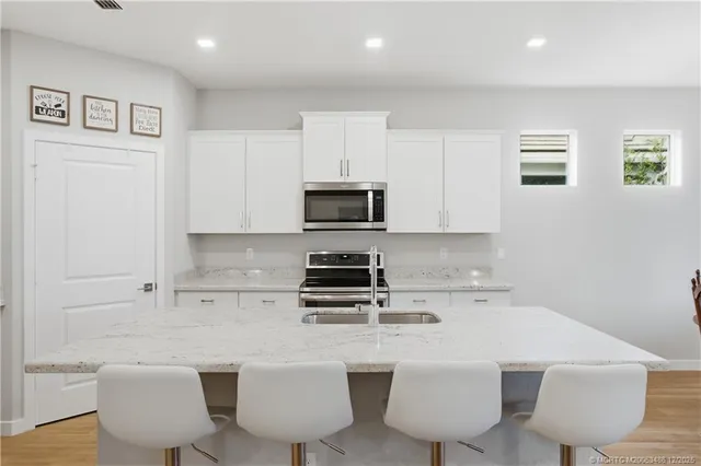 a kitchen with stainless steel appliances granite countertop a stove a sink a microwave a dining table and chairs