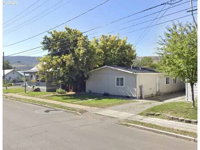 a view of a house with a yard and large trees