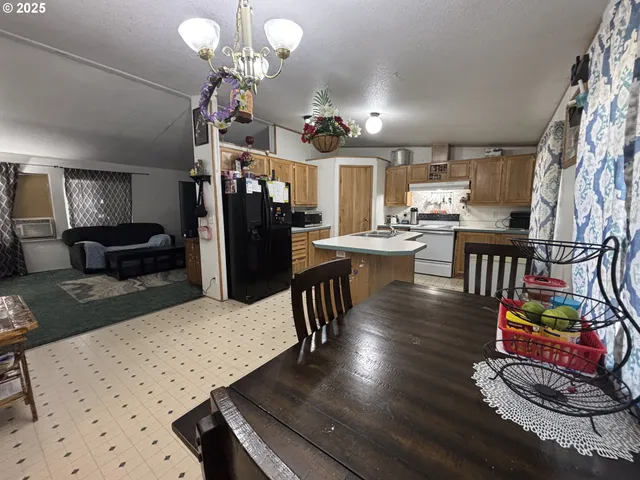 a living room with stainless steel appliances furniture a rug and a kitchen view