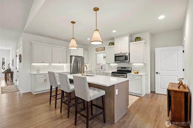 a kitchen with stainless steel appliances a dining table chairs stove and white cabinets