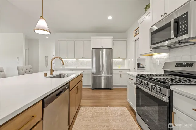 a kitchen with stainless steel appliances granite countertop a sink a stove a refrigerator cabinets and a counter top space