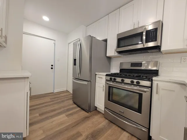 a kitchen with stainless steel appliances white cabinets a stove a microwave and a refrigerator