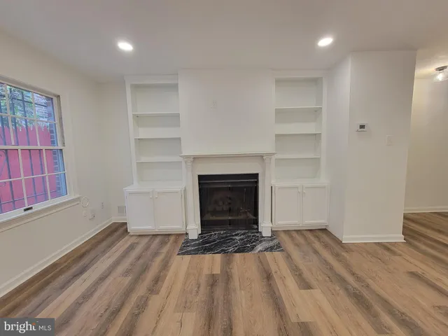 a view of a livingroom with wooden floor a fireplace and window