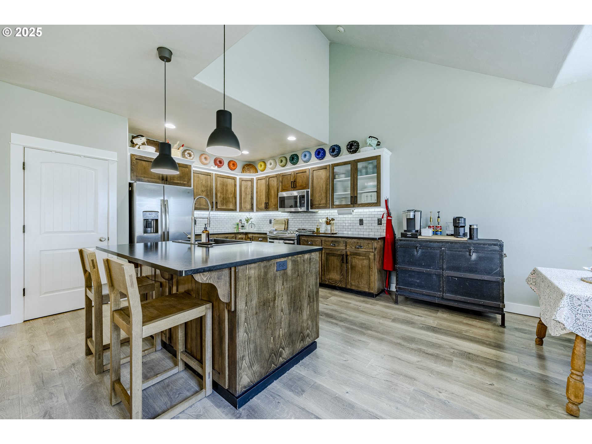 2409 Crowther Drive Eugene, OR 97404 - Photo 16 of 48 a kitchen with stainless steel appliances kitchen island granite countertop a table chairs and a wooden floor