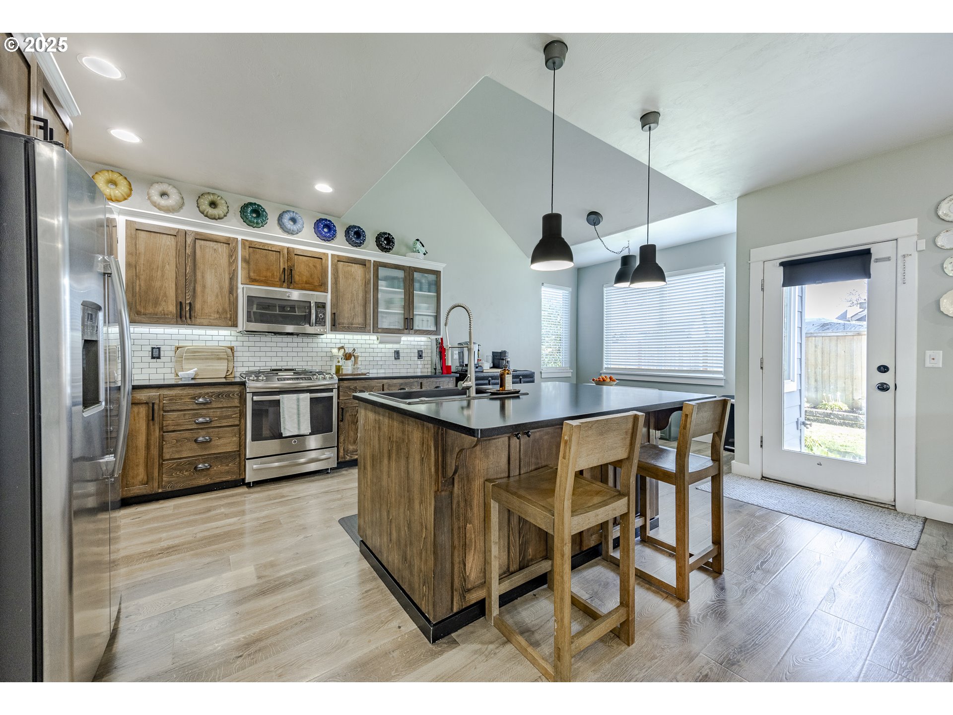 2409 Crowther Drive Eugene, OR 97404 - Photo 17 of 48 a kitchen with stainless steel appliances kitchen island granite countertop a table chairs sink and cabinets