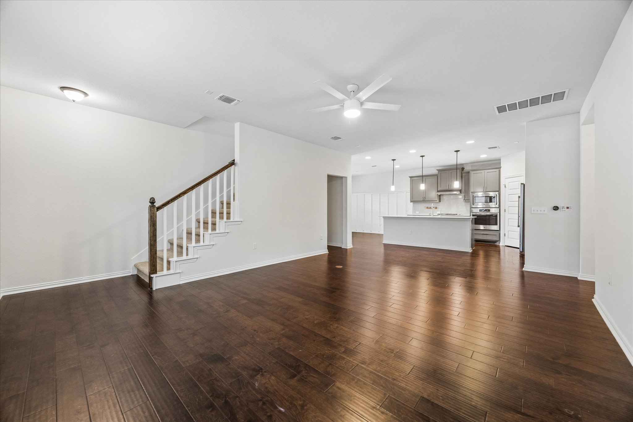 8816 Cattle Baron Path Austin, TX 78747 - Photo 12 of 32 a view of an empty room with wooden floor and a kitchen