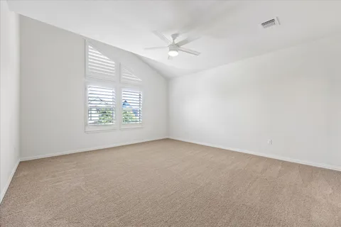 an empty room with windows and ceiling fan