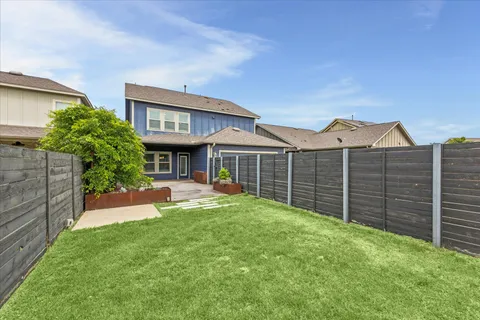 a view of a house with a yard and wooden fence