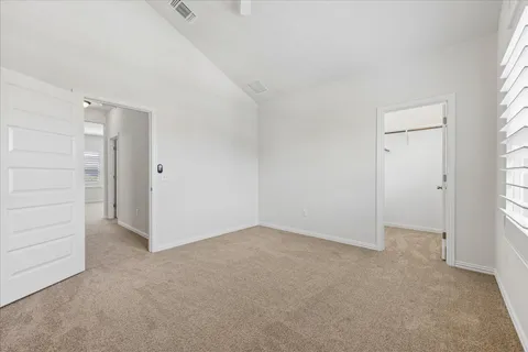 an empty room with chandelier fan and windows