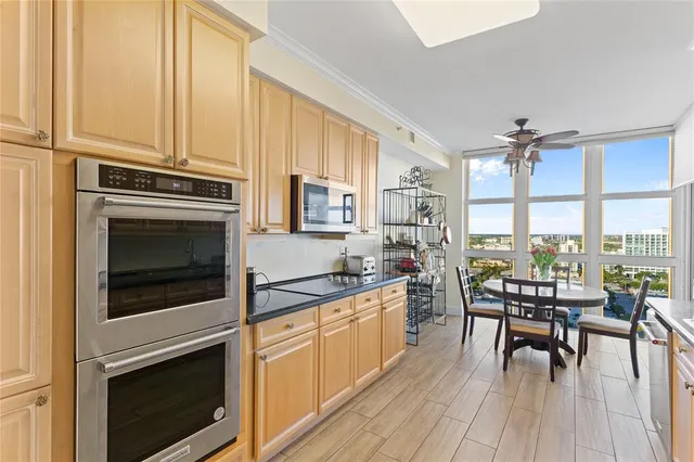 a kitchen with stainless steel appliances a stove a sink and white cabinets with wooden floors