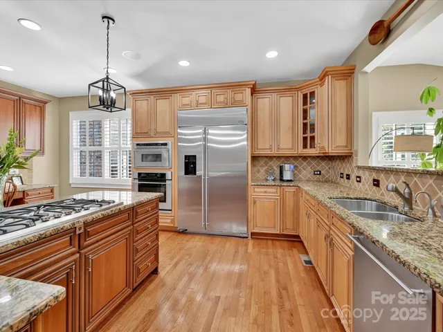 a kitchen with stainless steel appliances granite countertop a sink refrigerator and cabinets