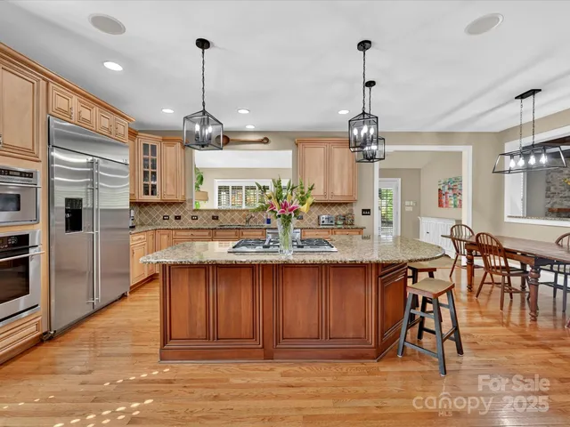 a kitchen with stainless steel appliances granite countertop wooden floor dining table and chairs
