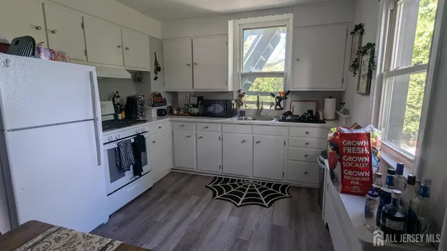 a kitchen with stainless steel appliances a stove a sink a refrigerator cabinets and wooden floor