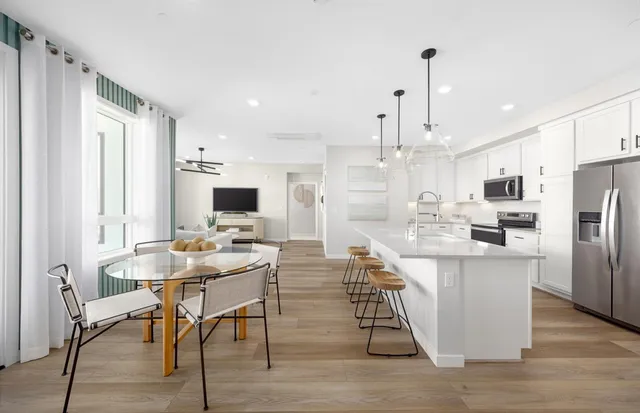 a kitchen with stainless steel appliances kitchen island granite countertop a table chairs and a wooden floor