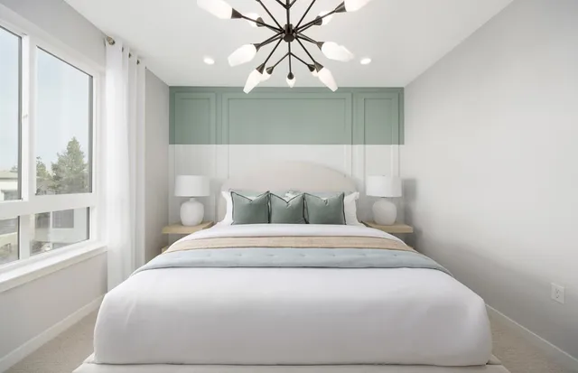 a large white bed in a small room next to a window